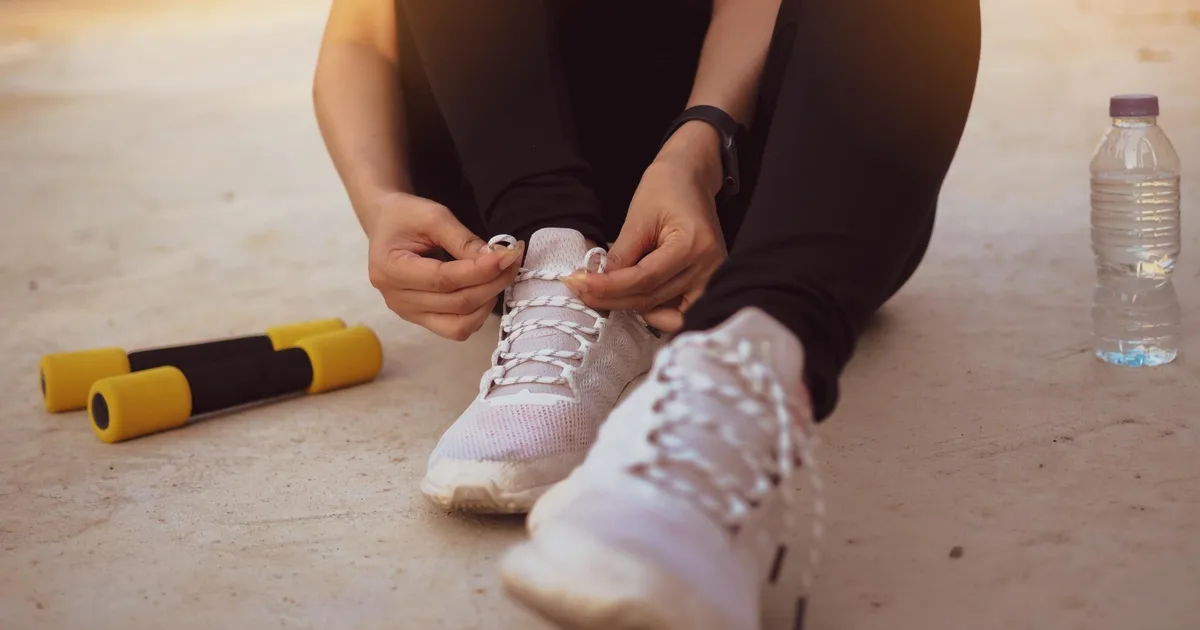 Deportista aficionado atándose las zapatillas antes de entrenar en casa