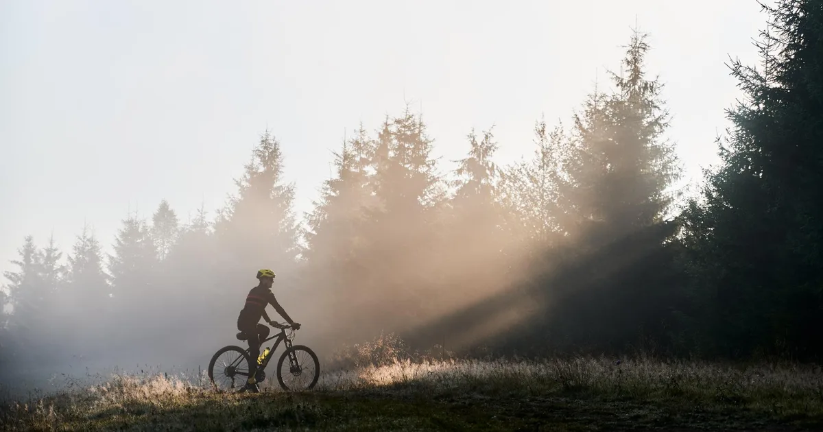 Ciclista amateur pedaleando por una carretera secundaria en una mañana fría de invierno