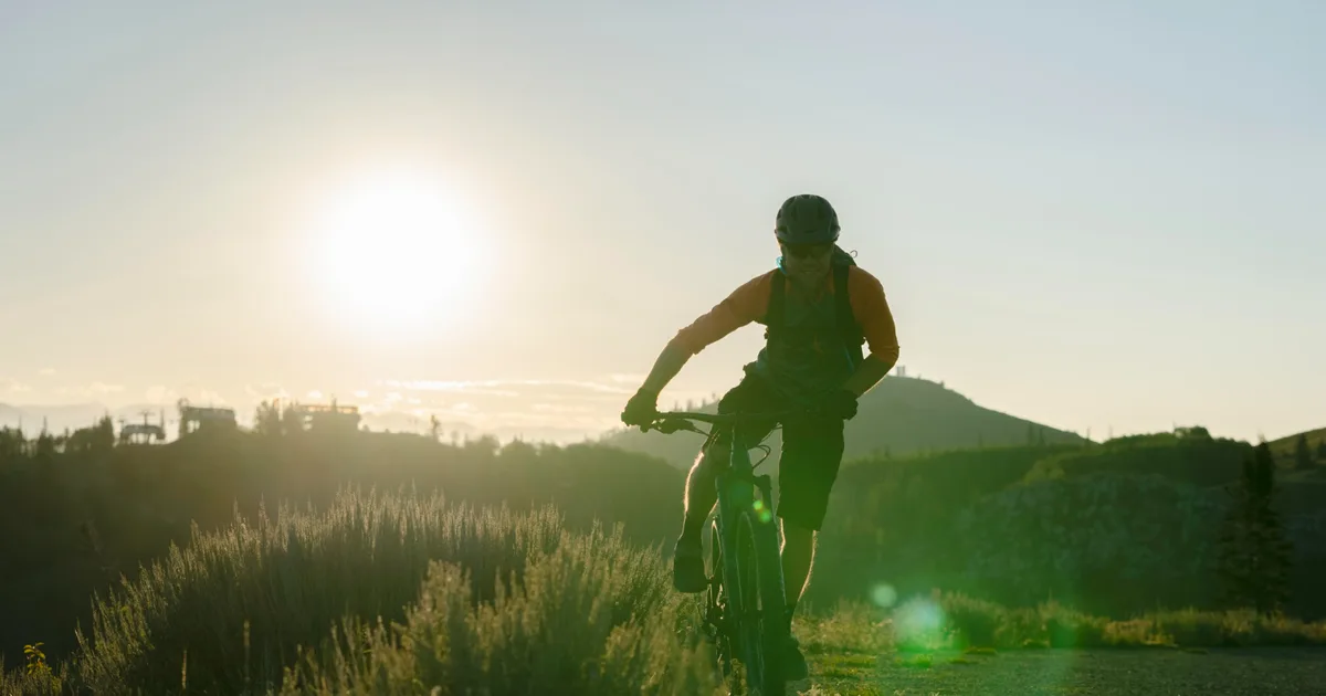 Ciclista amateur sonriente parado en lo alto de una cuesta contemplando el paisaje