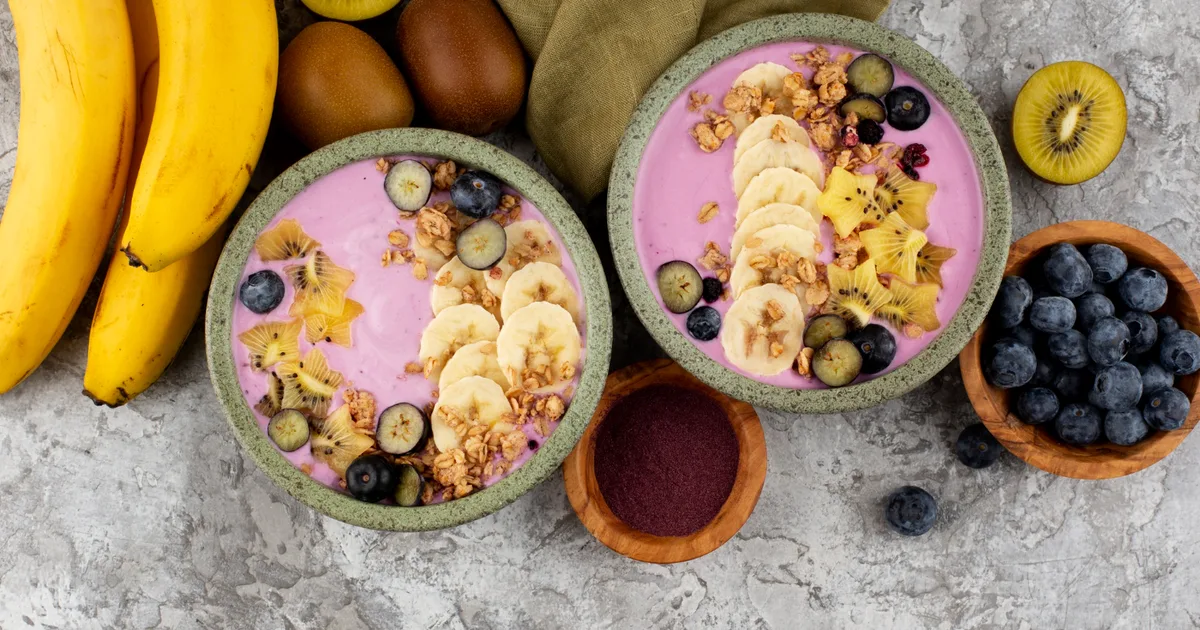 Desayuno saludable con yogur, avena, fruta y frutos secos sobre una mesa de madera