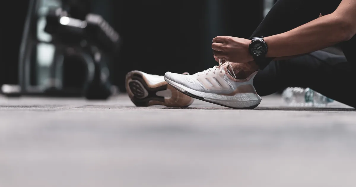 Persona atándose las zapatillas de deporte junto a la cama por la mañana