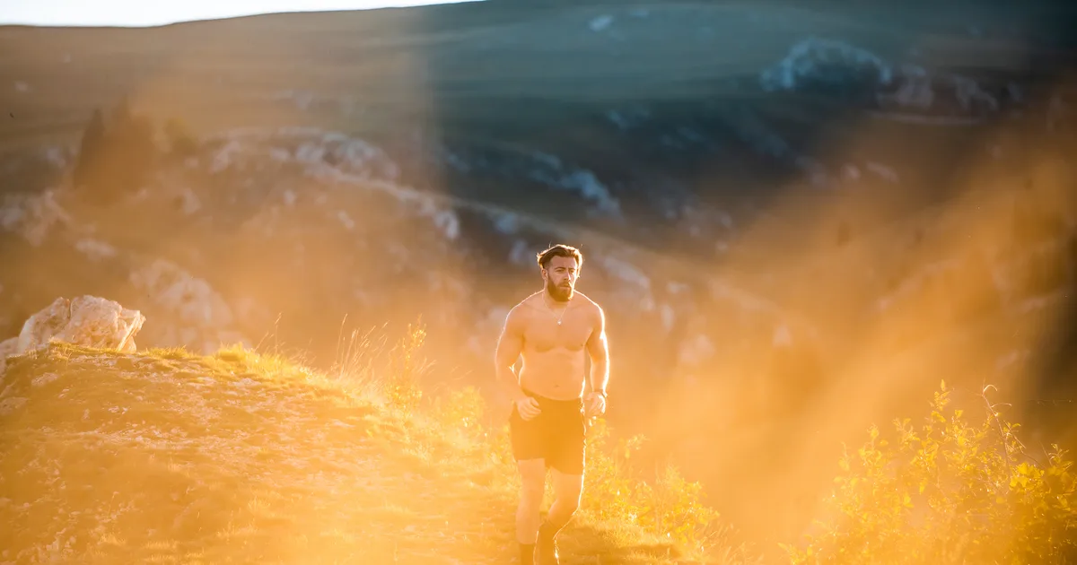Corredor por un sendero al amanecer con la luz dorada del sol bajo y sombras largas
