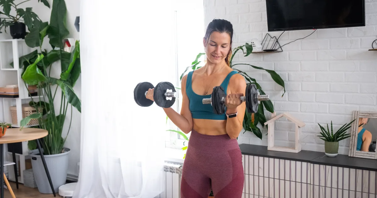 Mujer entrenando con mancuernas en el salón de su casa