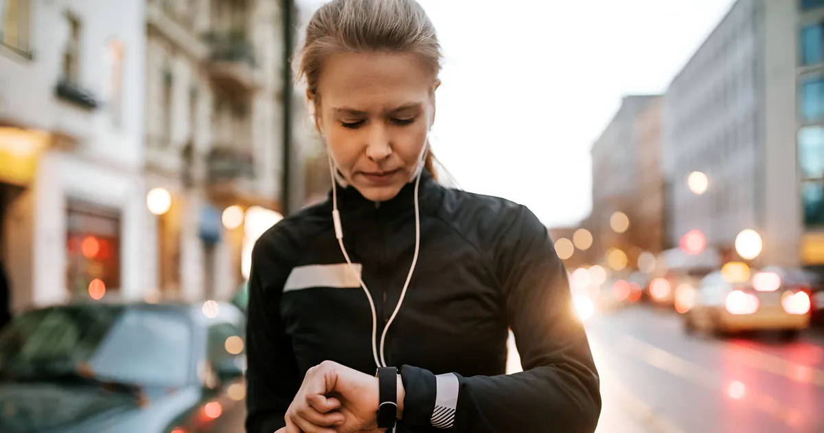 Corredora comprobando los datos de su reloj deportivo durante una salida por carretera