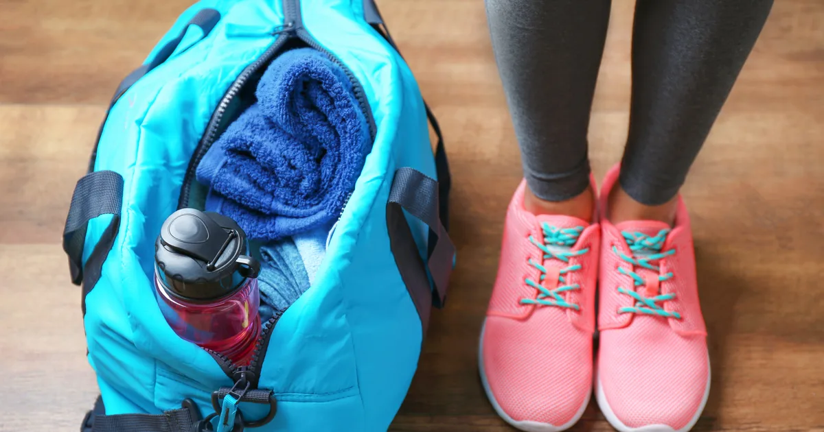 Mujer de pie junto a una bolsa de deporte preparada con la ropa y las zapatillas